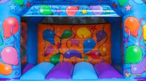 A balloon-themed bouncy castle with bright decorations, designed for fun and entertainment at outdoor gatherings.