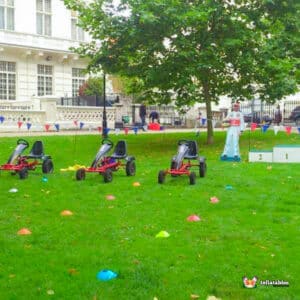 A row of colorful go-karts parked on a grassy area, ready for racing.