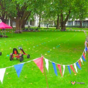 A vibrant lawn with a car and a go-kart placed prominently in the middle of the grassy area.