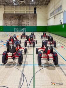 Several go-karts parked in a gymnasium, showcasing their vibrant designs and ready for action.