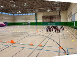 A lineup of go-karts in a gymnasium, displaying their unique designs and vibrant colors for an exciting race.