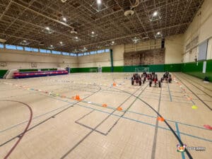 A group of colorful go-karts lined up in a spacious gymnasium, ready for racing.