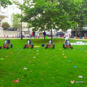 Several go-karts lined up on green grass, awaiting drivers for a fun racing experience.