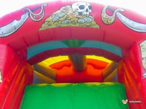 Brightly colored inflatable bounce house entrance featuring pirate-themed decorations, including a skull, coins, and vibrant rainbow hues.