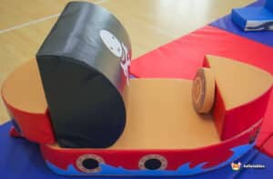 A colorful pirate ship-shaped play mat spread on the floor, designed for children's soft play activities.