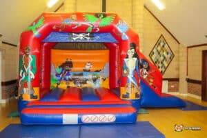 A colorful pirate-themed bouncy castle featuring sails, skulls, and crossbones, inviting children to play and explore.