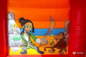 A cartoon pirate character happily jumps on a red inflatable bouncy castle, embodying a playful and festive spirit.