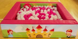 A whimsical pink castle adorned with pink and white balloons, creating a festive atmosphere for Princess Soft Play.