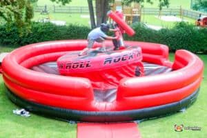 Two boys compete on an inflatable gladiator duel, enjoying a lively and energetic game together.