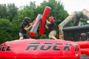 Two men are having fun battling on an inflatable gladiator duel, showcasing their playful rivalry.