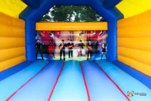 Interior of a colourful bouncy castle featuring a stage backdrop with musicians, inviting fun and play. Bright yellow and blue design.
