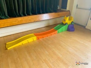 A playful slide with a toy car perched at the top, ready for a thrilling ride in a fun-filled space.