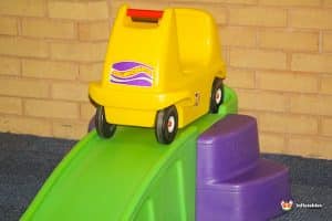 A colorful slide with a toy car positioned at the top, ready for a fun descent in a playful setting.