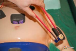 A person holds a device connected to another person's body in the Sawbones Electronic Operation Game.