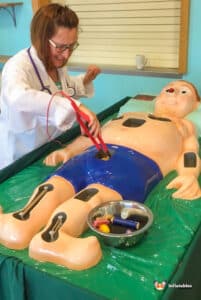 A woman in a lab coat operates on a man in the Sawbones Electronic Operation Game, showcasing a playful medical theme.