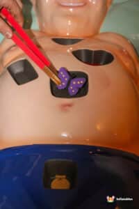 A participant uses a device linked to another's body in the Sawbones Electronic Operation Game.