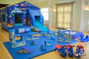 5. A cheerful play area featuring a sea-themed bouncy castle, a slide, and an array of soft play toys for young children.