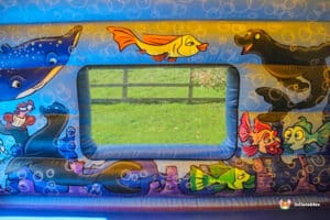 A playful bouncy castle decorated with a fish and sea animals, perfect for a fun outdoor event.