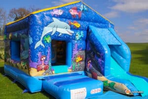 A colorful bouncy castle featuring a dolphin and fish theme, inviting children to play and enjoy a fun-filled experience.