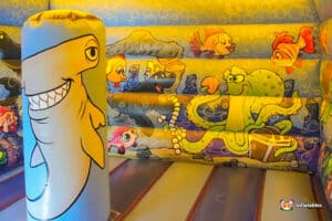 A vibrant bouncy castle adorned with a shark and playful cartoon characters, inviting children to jump and play.
