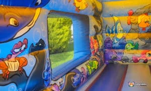A colorful bouncy castle featuring various cartoon characters, inviting children to play and have fun.