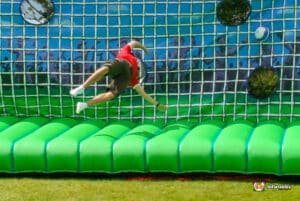 A man leaps over a soccer goal showcasing his agility and skill in the game.