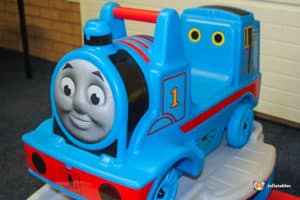 A lively Thomas the Train ride located in a hall, with bright colors and children eagerly waiting to hop on.