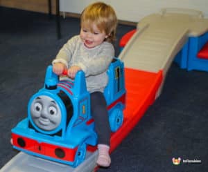 Kids happily enjoying a Thomas the Train ride at a party, with vibrant decorations and cheerful ambiance in the background.