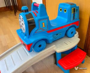 A Thomas the Tank Engine slide positioned in a hall, providing a playful attraction for kids in a spacious indoor setting.