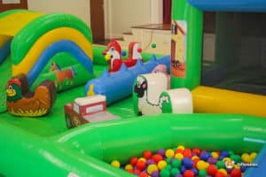 A colorful play area featuring a ball pit, an inflatable slide, and various farm animal decorations for children to enjoy.