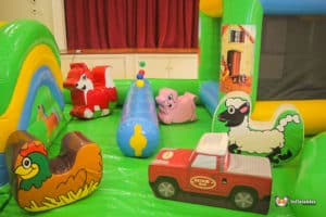A cheerful play zone for toddlers, showcasing a bouncy castle, slide, and a variety of engaging toys for little ones.