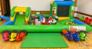 A lively play area with a ball pit, inflatable slide, and cheerful farm animal designs, inviting children to have fun.