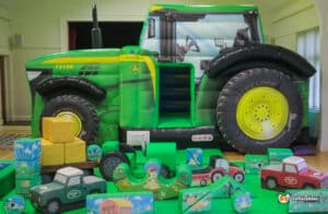 Large inflatable tractor with toys and a play area, part of the Tractor B&S Deluxe Package, designed for children's entertainment.