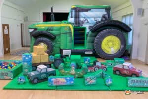 Large inflatable tractor with a play area and toys, featured in the Tractor B&S Deluxe Package for children's enjoyment.