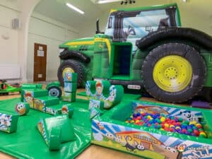 A vibrant play area showcasing a tractor and other toys, designed as the Tractor Bounce & Slide Soft Play Package.
