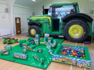 A colorful play area with a tractor and various toys, part of the Tractor Bounce & Slide Soft Play Package for children.