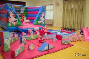 A low unicorn-themed bouncy castle surrounded by colourful soft play toys for children to enjoy.