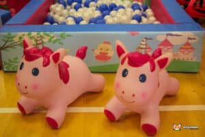 Two pink unicorn hoppers joyfully surrounded by a vibrant array of balls in a playful ball pit.