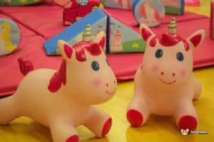 A playful scene featuring two pink unicorn toys on the floor of a vibrant playroom, inviting imaginative play.