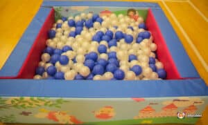 A vibrant ball pit overflowing with blue and white balls, designed with a unicorn theme.