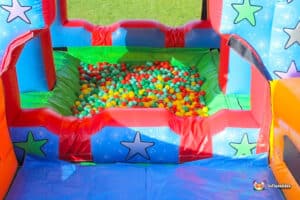Colorful ball pit filled with red, green, and yellow balls, surrounded by a bright inflatable play structure with star designs.