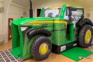 A large inflatable tractor featuring a slide, designed for children's play and outdoor entertainment.