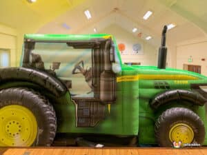 A colorful inflatable tractor with an attached slide, providing a fun play area for kids at outdoor events.