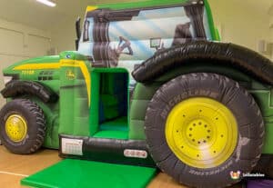 A colorful large inflatable tractor featuring a fun slide, perfect for children's outdoor play and entertainment.