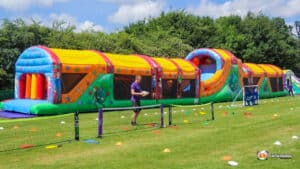 A large inflatable obstacle course named 'The Colossal' set up on a grassy field.