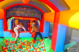 A colorful bouncy castle named Colossal with children playing and colorful balls scattered around.