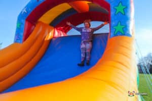 A girl gleefully descends an inflatable slide capturing the thrill of outdoor play and adventure.