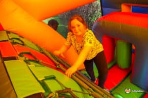 A girl enjoys playing in inflatable bouncy castle, filled with vibrant colours and fun obstacles.