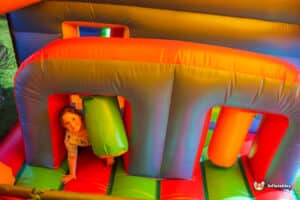 A girl is happily bouncing in through biff and bash inflatables, surrounded by bright colors and playful obstacles.
