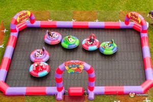 Inflatable bumper cars on a grassy field with people enjoying a playful game together.